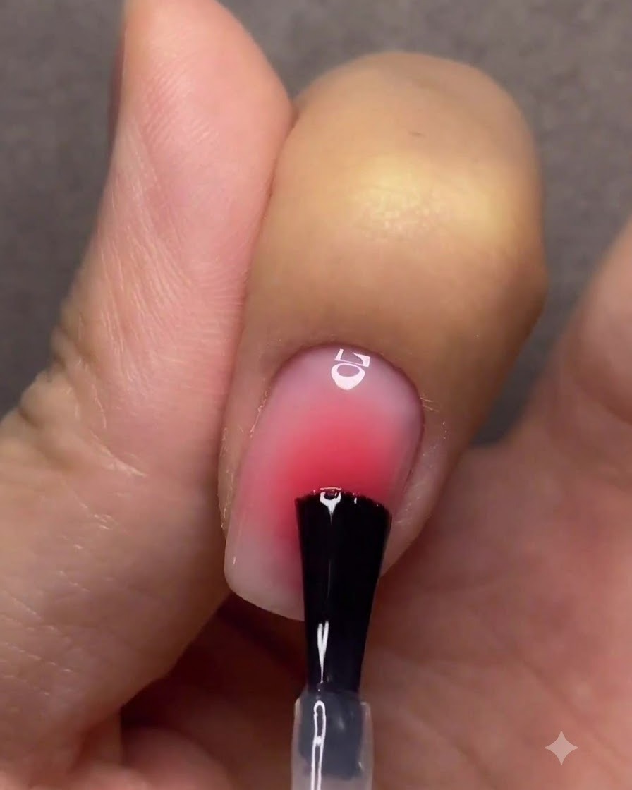 Eine Hand mit fertigen Gradienten-Nägeln härtet unter einer pinkfarbenen UV- und LED-Nagellampe aus.