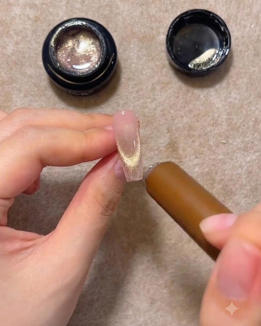 Ein zylindrischer Magnetstab schwebt in der Nähe der Nagelspitze einer Verlängerung und zieht den Glitter in eine leuchtende U-Form.