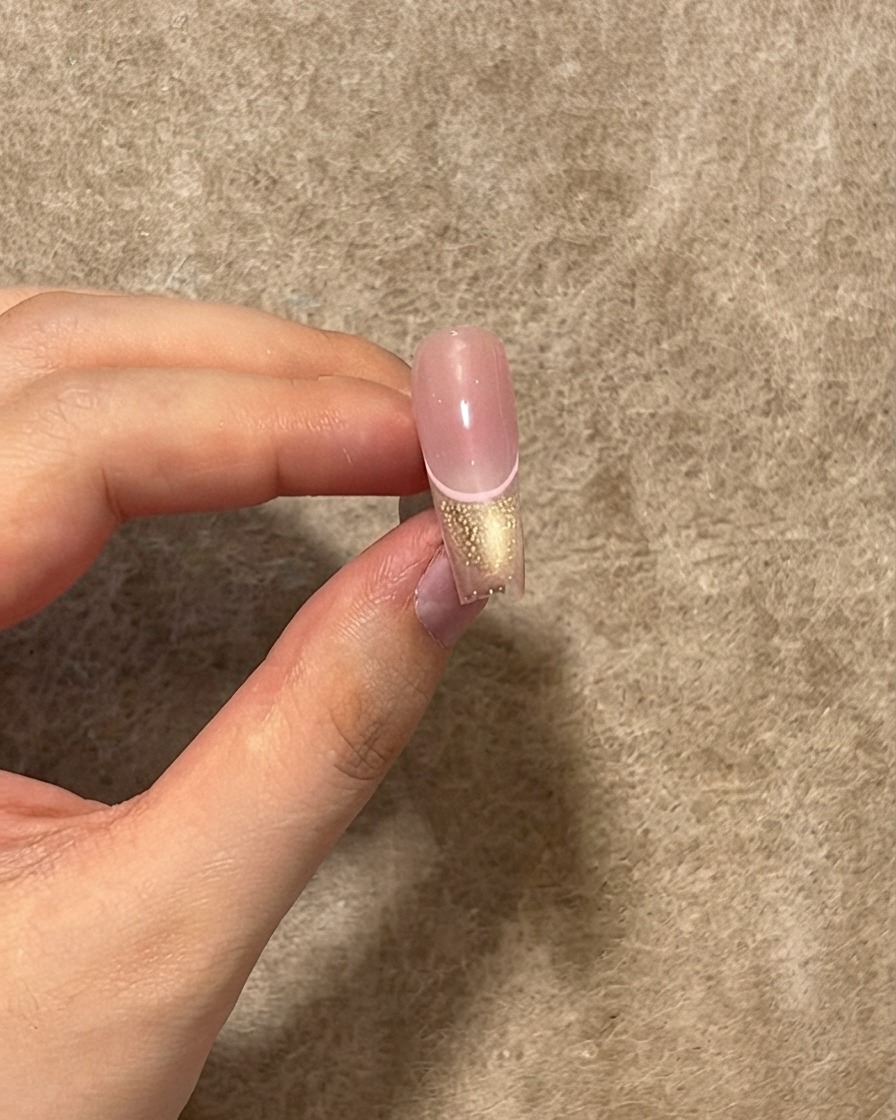 Ein fertiger Nagel zeigt eine glänzende Top-Coat-Schicht, die über der rosa Linie, der Cat-Eye-Spitze und dem Blush-Zentrum aufgetragen wurde.