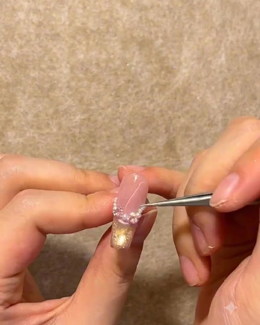 Eine Metallpinzette platziert winzige weiße Perlen und Strasssteine entlang der French-Smileline eines Nagels.