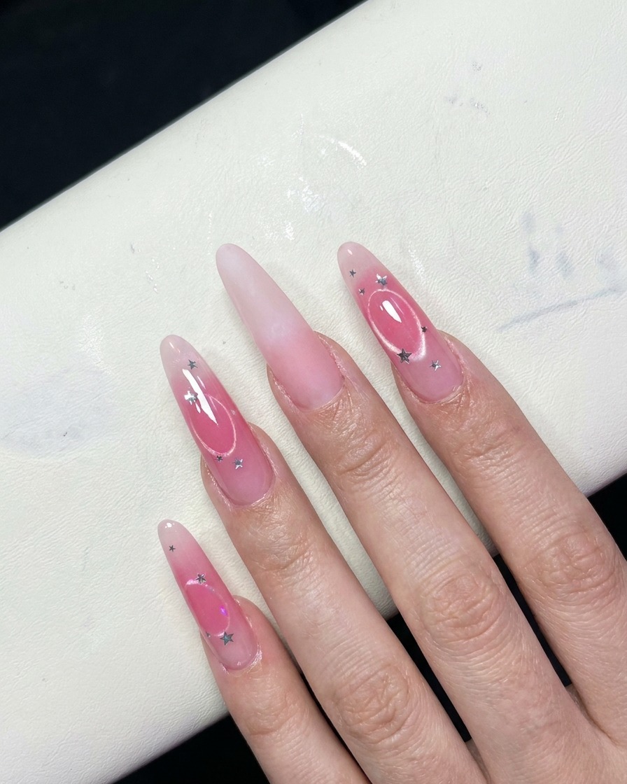 Eine Nahaufnahme von Fingern, die einen rosafarbenen Blush-Farbverlauf in der Mitte der Nägel zeigen.