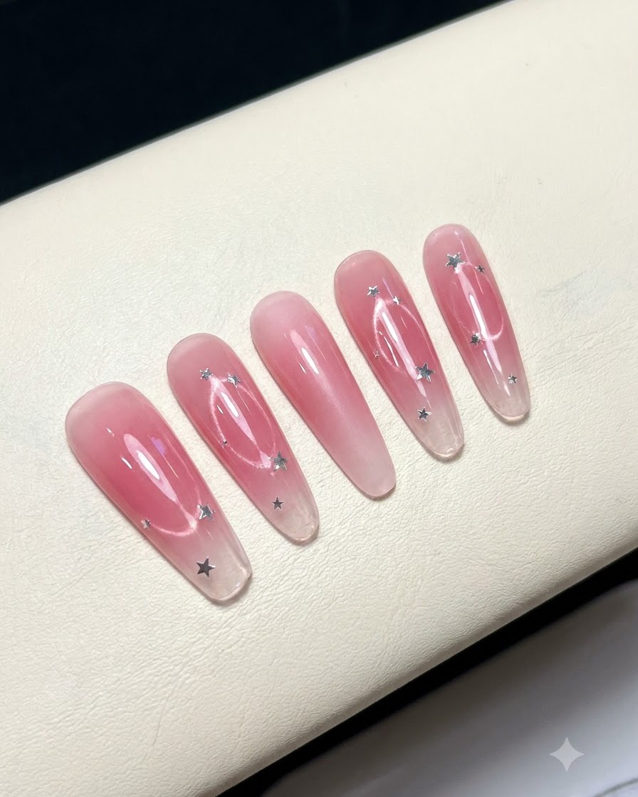 Fünf künstliche Nägel auf einer weißen Oberfläche zeigen ein rosafarbenes Blush-Mitteldesign.