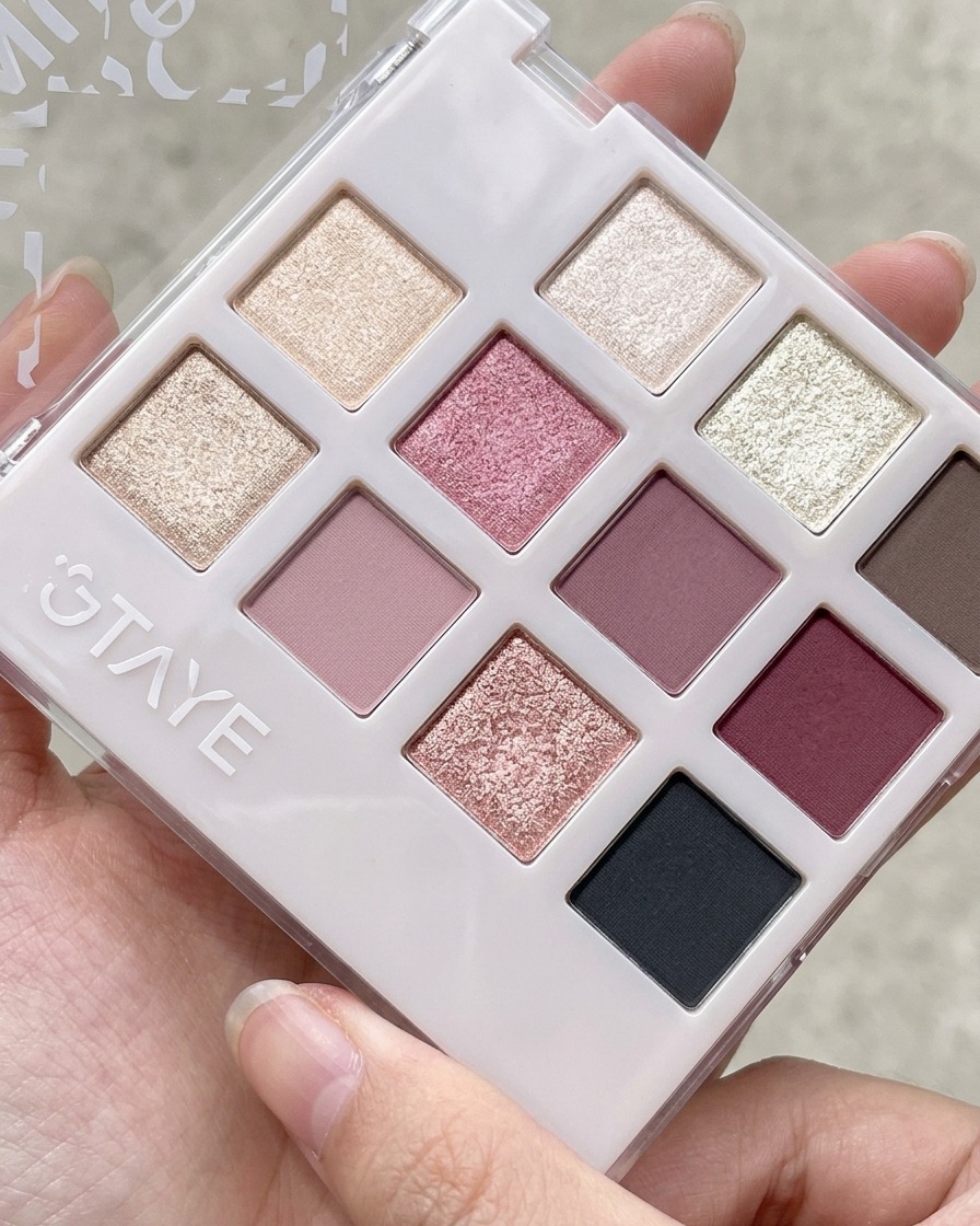 Ein Silikonwerkzeug nimmt pfirsichrosa Gel aus einer Mehrkammer-Lidschatten- und Gel-Palette auf.