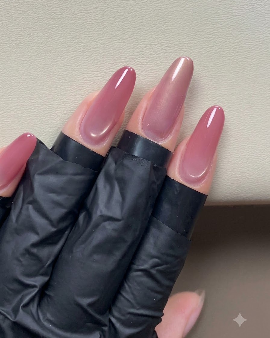 Eine Hand hält einen Stiftmagneten in die Nähe eines glänzenden roségoldenen Cat-Eye-Nagels, um einen Seitenlicht-Effekt zu formen.
