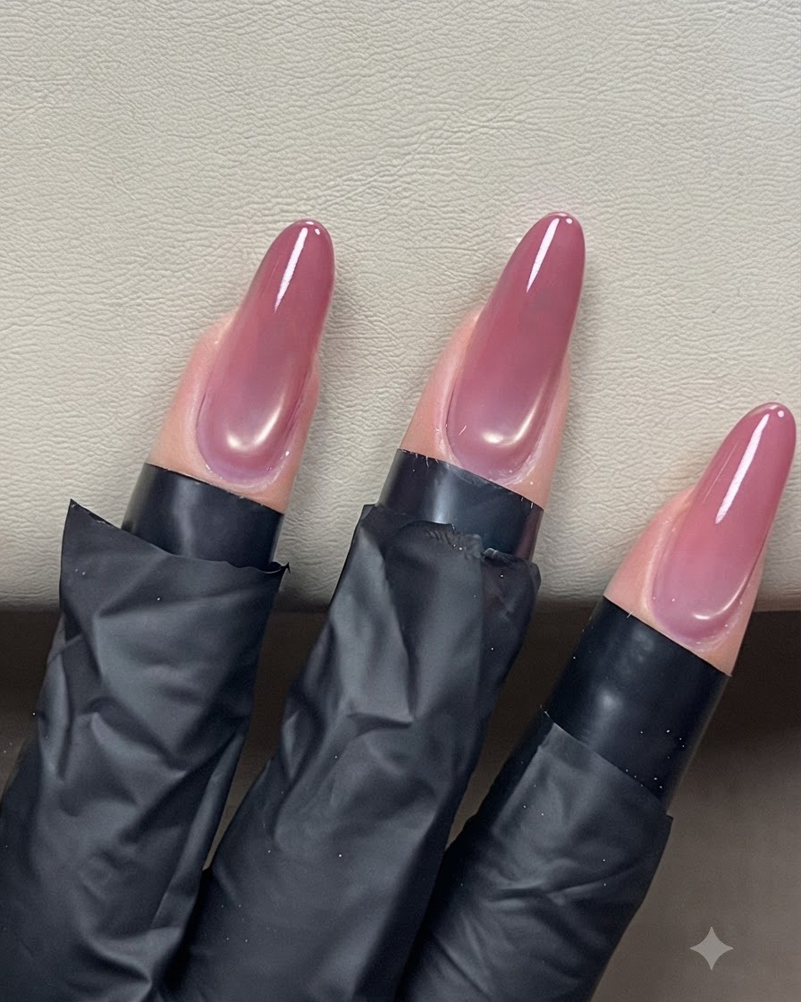 Ein Nagelpinsel gleitet mit einem Klarlack über mandelförmige Cat-Eye-N Nägel für ein glänzendes Finish.