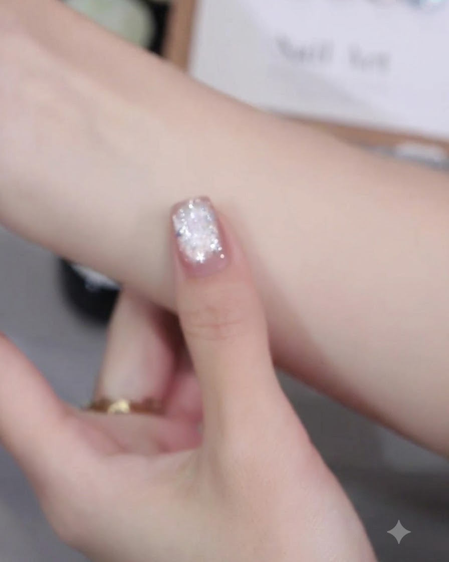 Ein Nagelpinsel trägt rosa Cat-Eye-Gellack gleichmäßig auf die Nageloberfläche auf.