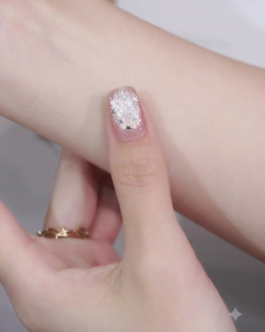 Nahaufnahme eines manikürten Nagels mit einem Stern-Glitterteilchen, das auf der Spitze über einem Rand-Nail-Art-Detail platziert ist.