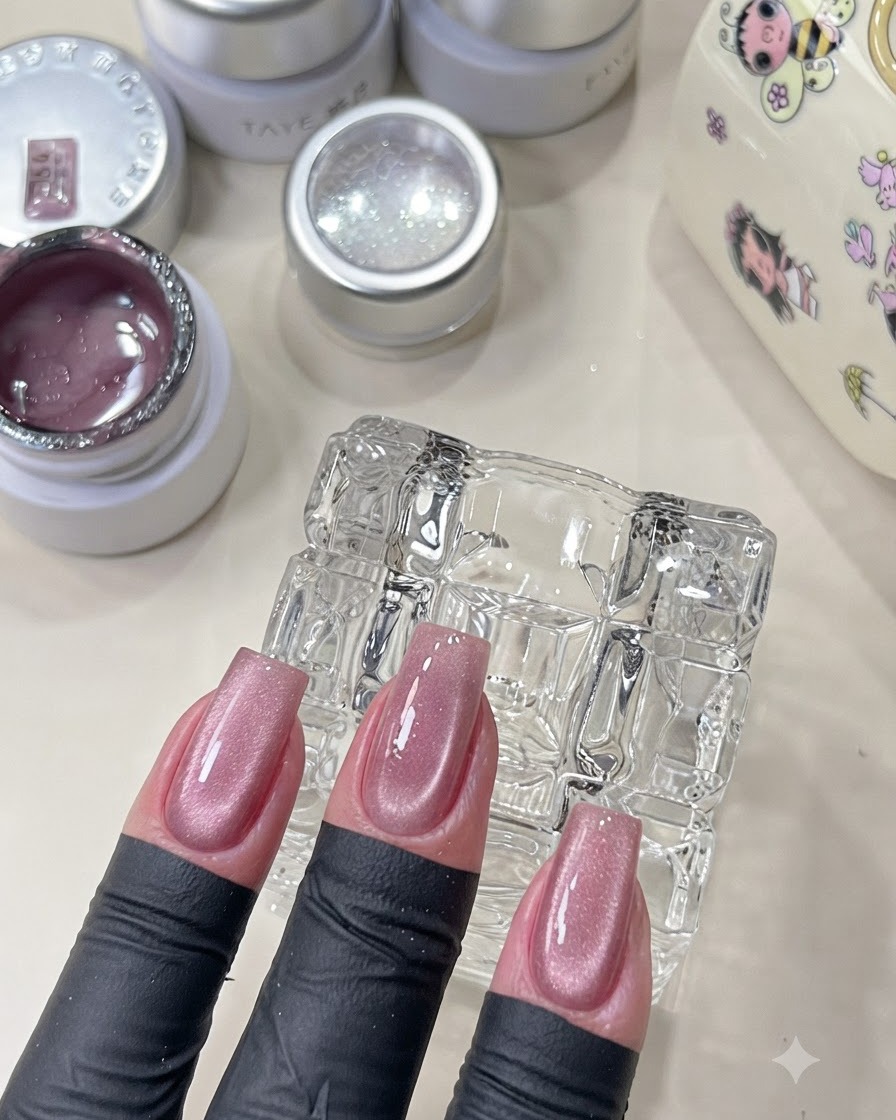 Eine Hand zeigt ausgehärtete rosa Cat-Eye-Nägel mit einem schimmernden Finish.