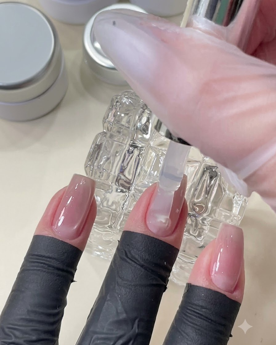 Ein Pinsel trägt einen klaren Top-Coat-Gel auf, um die Nageloberfläche über der eingebetteten Nail-Art zu glätten und zu versiegeln.