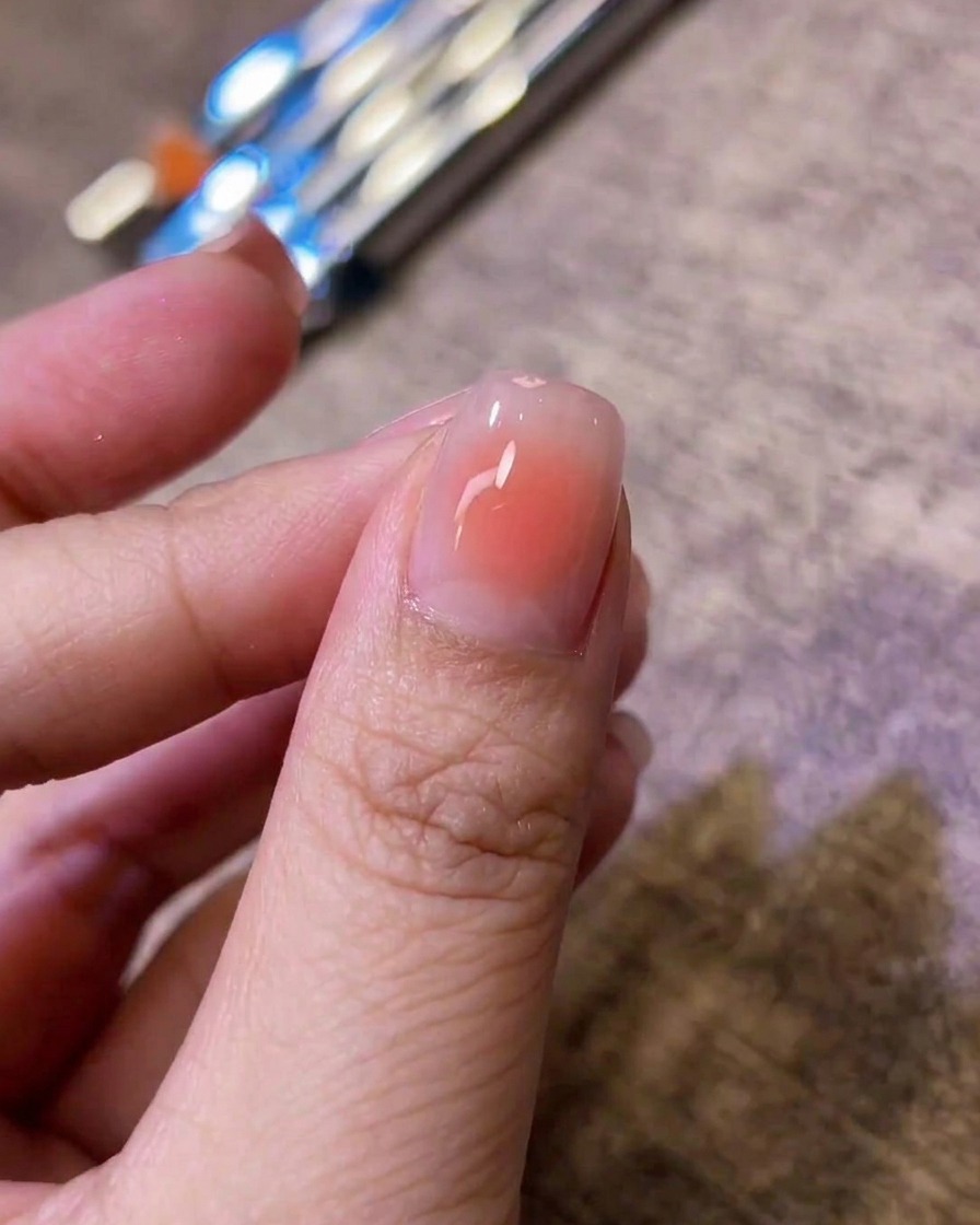 Nahaufnahme eines glänzenden Fingernagels mit einer sanft verblendeten rosa Blush-Mitte auf einer Nude-Basis.