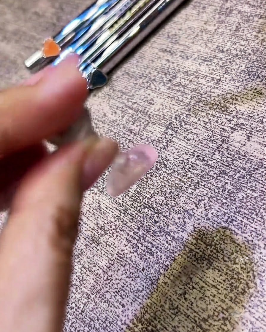 Ein Pinsel trägt einen klaren Top Coat über einen Nagel mit Chrom-Finish auf.