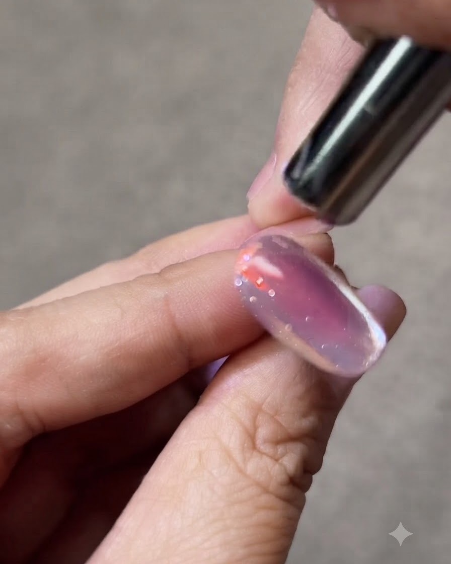Ein kleiner Magnet wird dicht neben einen Cat-Eye-Gelnagel gehalten, um den leuchtenden Lichtstreifen zu formen.