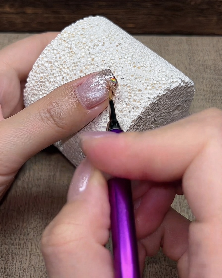 Ein feiner Detailpinsel verwischt Glitzerpartikel leicht nach hinten von der Spitze zur Nagelhaut.