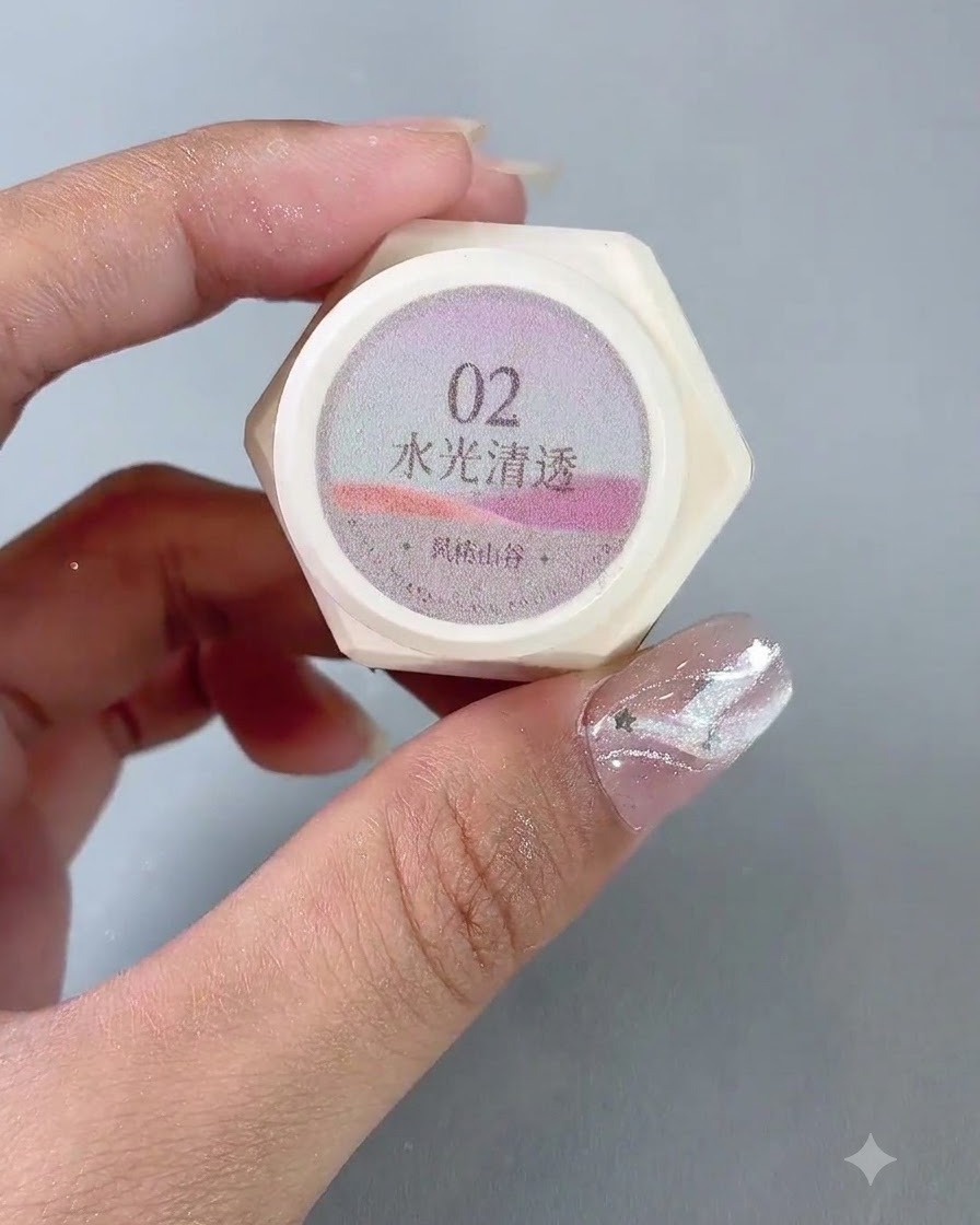 Ein Paar Hände hält ein Gläschen mit der Nummer 2 Water-Gloss transluzentem Cat-Eye-Gelpolish.