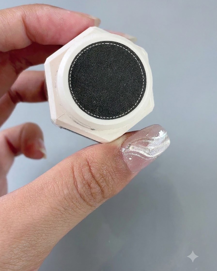 Ein Behälter mit Struktur-Styling-Gel liegt neben einem Nagel mit angebrachter French-Aufkleberschablone.