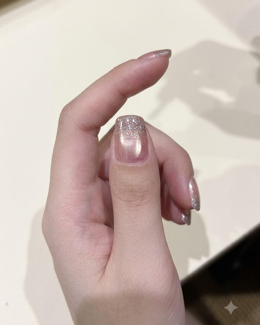 Ein Lackierpinsel trägt eine Schicht glitzerndes Diamant-Glittergel auf einen ausgehärteten Nagel auf.