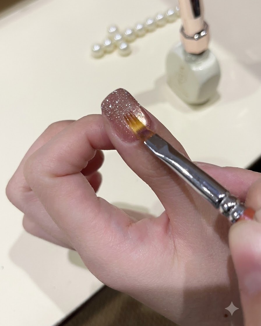 Ein feiner Pinsel glättet glitzerndes Glittergel auf der Oberfläche eines manikürten Nagels.