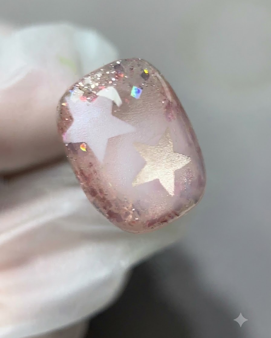 Eine detaillierte Nahaufnahme zeigt, wie rosa Glittergel um die Ränder des Nagels aufgetragen wird.