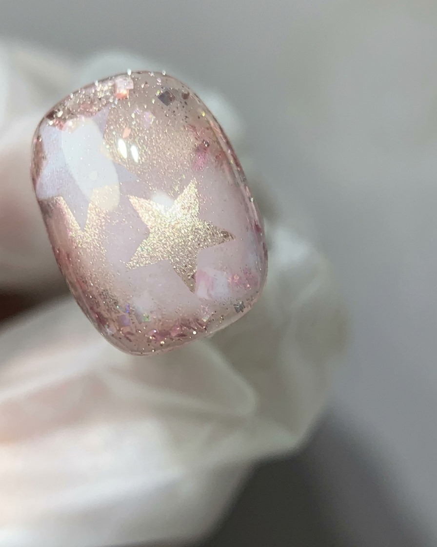 Ein Magnetstab wird über einen Nagel mit rosa Cat-Eye-Gel gehalten, um die schimmernde Reflexion zu einem Glaskugeleffekt zu konzentrieren.