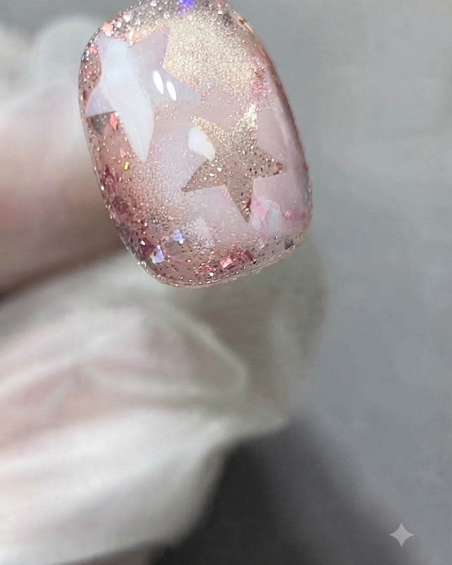 Ein Sternschablonen-Sticker wird präzise auf der Oberfläche eines verzierten Gel-Nagels angebracht.