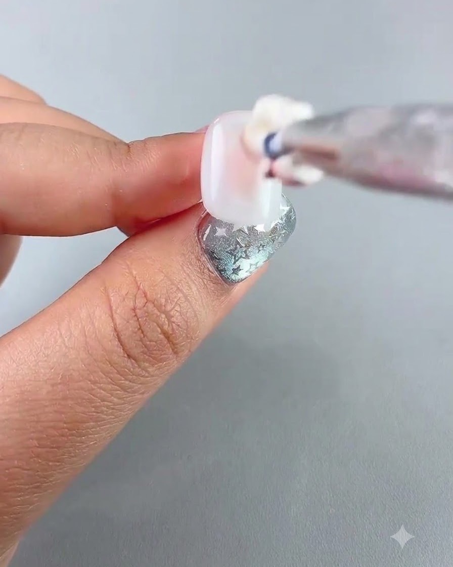 Eine detaillierte Ansicht eines Pinsels, der ein rosafarbenes Tupf-Gel auf die Mitte eines Nagels aufträgt.