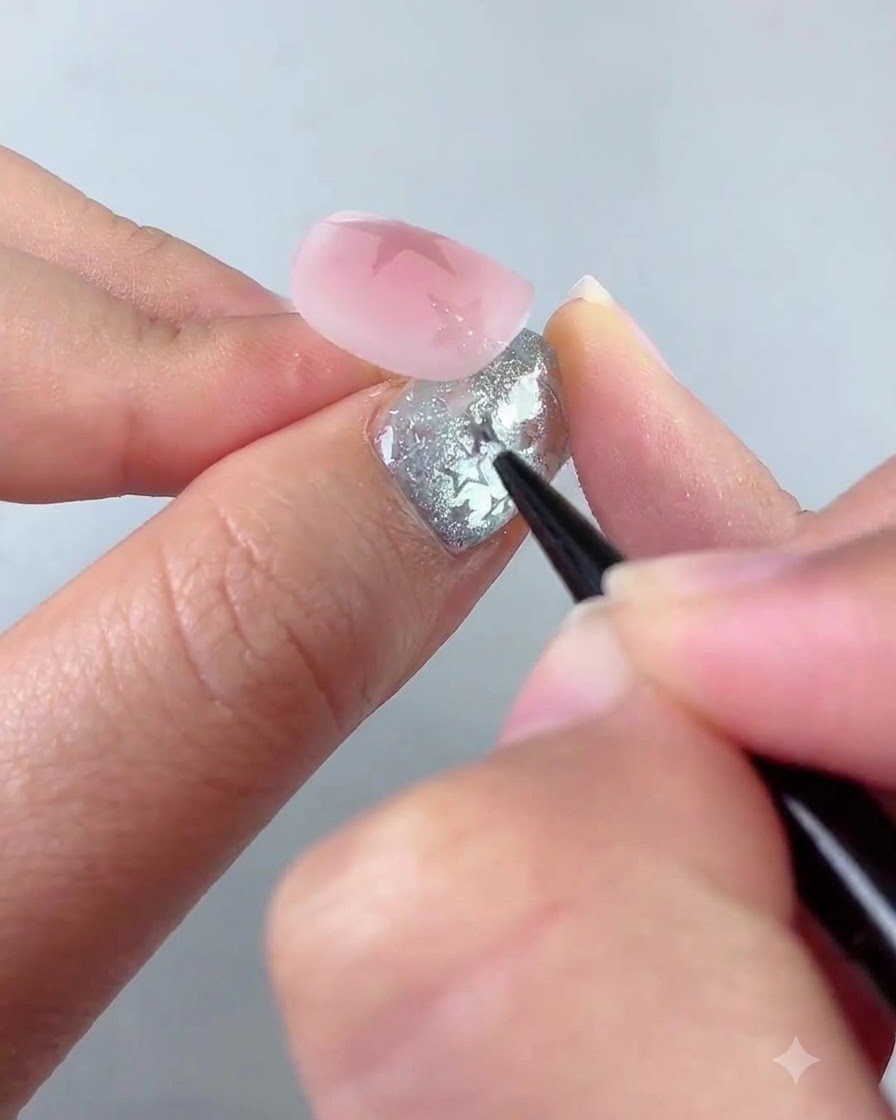 Ein Liner-Pinsel verziert eine kleinere Sternform in der unteren linken Ecke eines rosa Nagels.