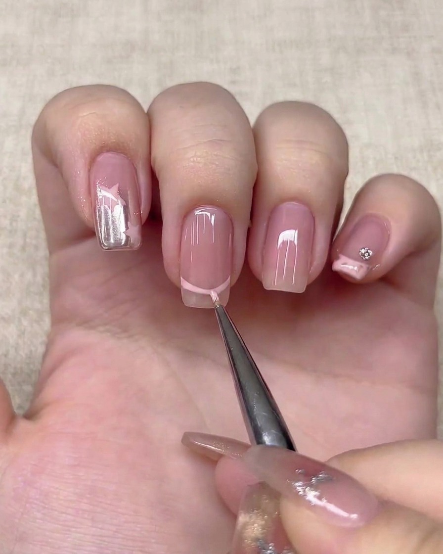 Ein feiner Liner-Pinsel zeichnet eine hellrosa French-Tip-Linie auf einen Nagel.