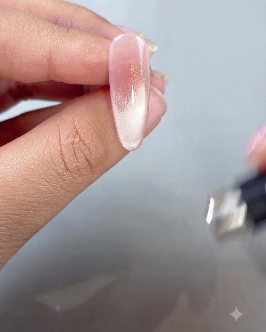 Ein Magnetstab wird in die Nähe einer lackierten Fingerspitze gehalten, um den Cat-Eye-Schimmer in einen French-Tip-Stil zu bringen.