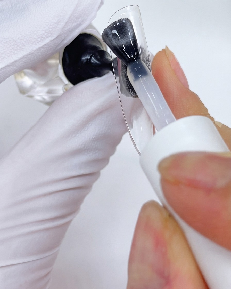 Ein Pinsel, der eine Überzugsschicht auf einem transparenten Nagel-Displayständer aufträgt.