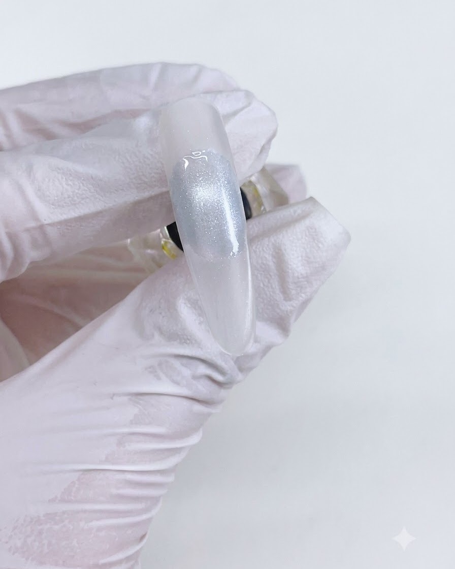 Eine fertige Cat-Eye-Gelperle auf einem Nagel nach dem Aushärten unter einer Lampe.