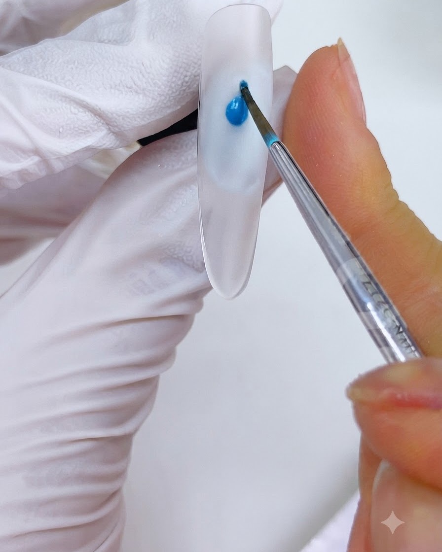 Ein feiner Pinsel platziert einen Tropfen himmelblaue Tinte auf ein Nageldesign.