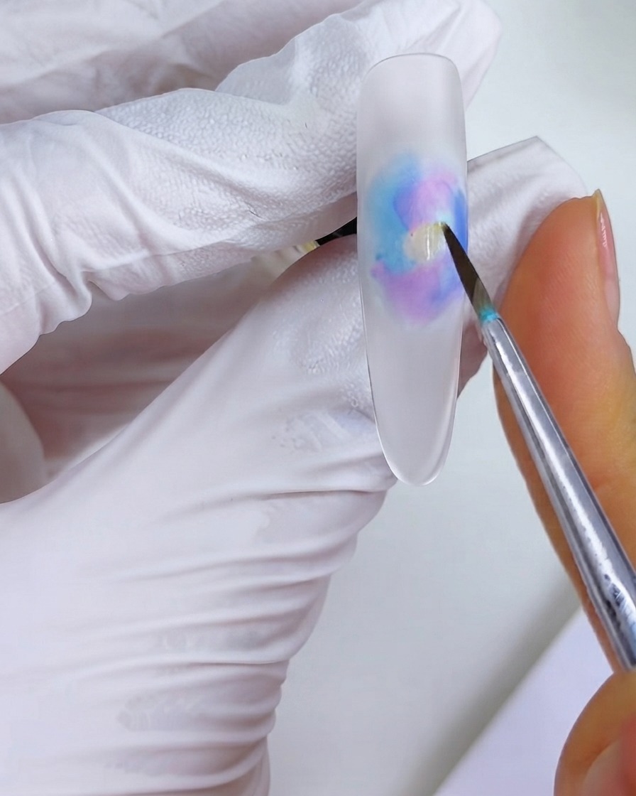 Ein feiner Pinsel platziert einen Klecks Orangetinte in die Mitte des Aquarell-Blühe-Musters.