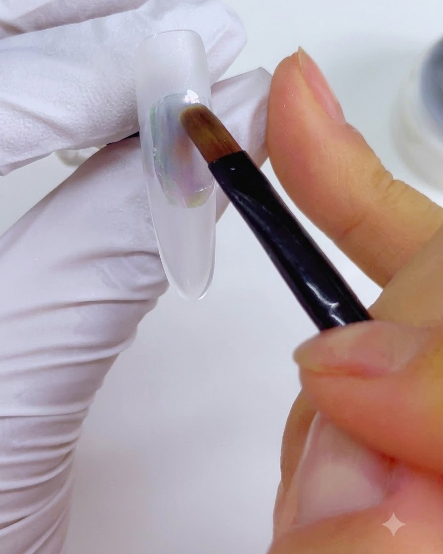 Ein Detailpinsel, der mit Nagel-Cleanser angefeuchtet ist, wird sanft über die mehrfarbige Tintenapplikation auf dem Nagel gezogen.