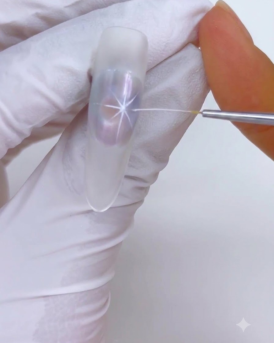 Ein feiner Liner-Pinsel zeichnet weiße Sternen-Highlights über ein durchsichtiges Nageldesign.