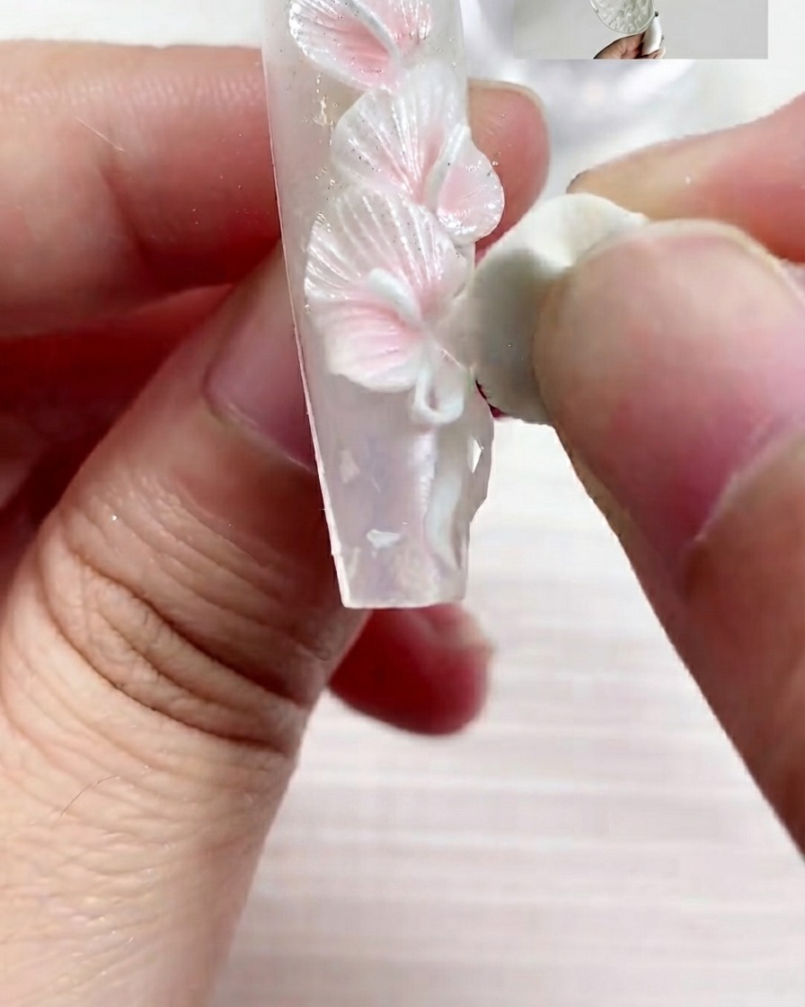 Ein flacher Pinsel trägt S03 Perltextur-Gel in glatten Strichen auf die Nageloberfläche auf.