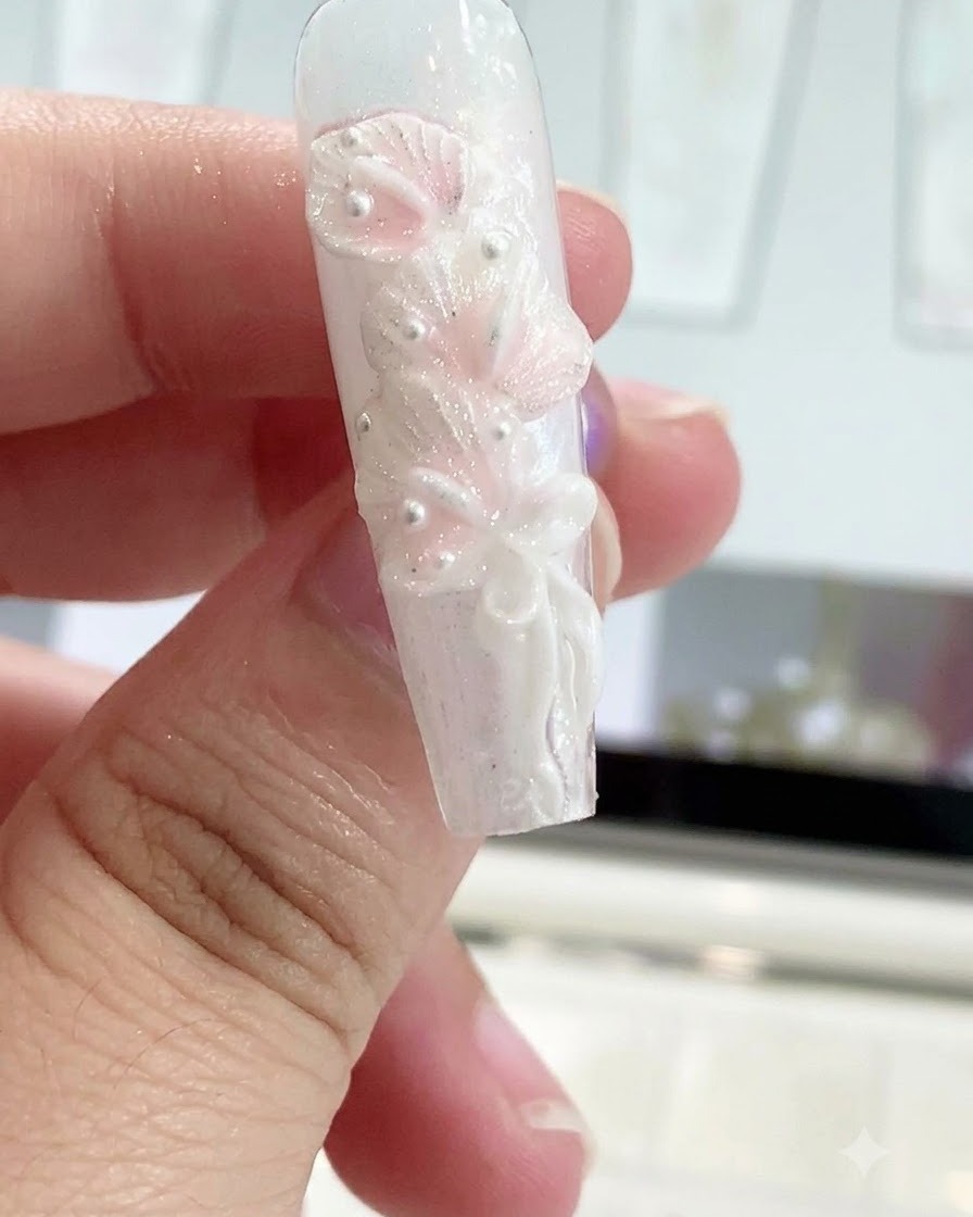 Ein Silikon-Formstift glättet einen Schleifenknoten auf einem skulpturierten Nageldesign.