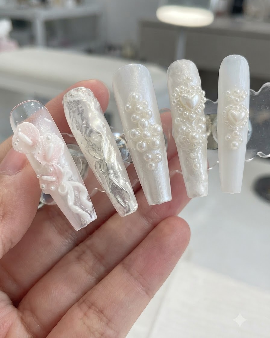 Ein Display-Ständer präsentiert 3D-Perlen- und Blumen-Nageldesigns nach dem Abkehren von überschüssigem Schimmerpulver.
