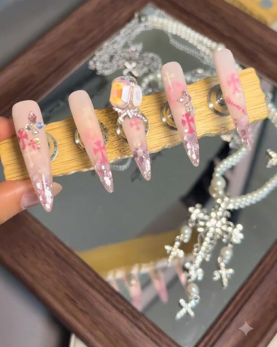 Ein Präsentationsständer zeigt ein Set fertiger Nagelkunstwerke mit einem prominenten großen Kristall und Schleifen-Charm auf dem Mittelnagel.