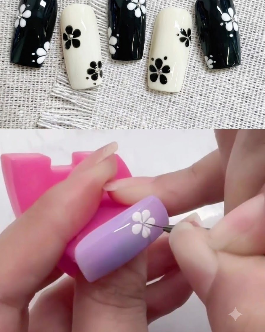 Ein kleines Dotting Tool platziert einen schwarzen Mittelpunkt in ein weißes Blumendesign auf einem lila Nagel.