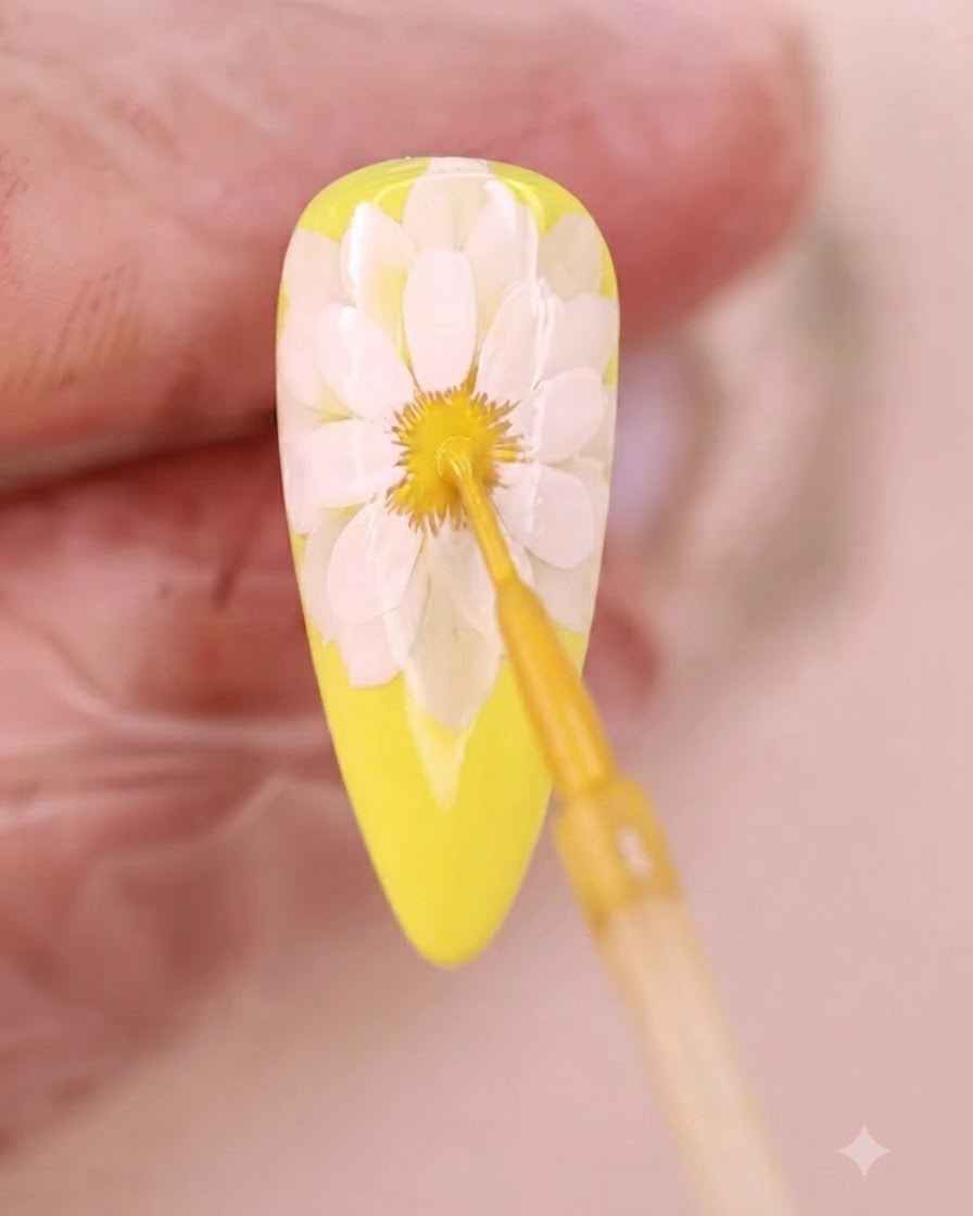 Ein feiner Pinsel trägt gelbe Flüssigkeit auf die verlaufende Mitte der Blume auf.