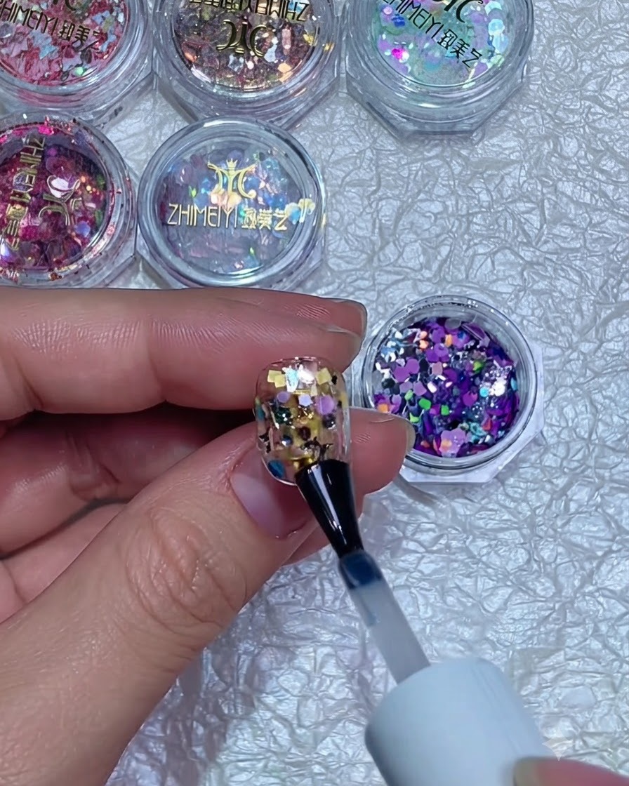Ein Nagelbuffer, der die Oberfläche eines ausgehärteten, mit Glitter versiegelten Nagels glättet.