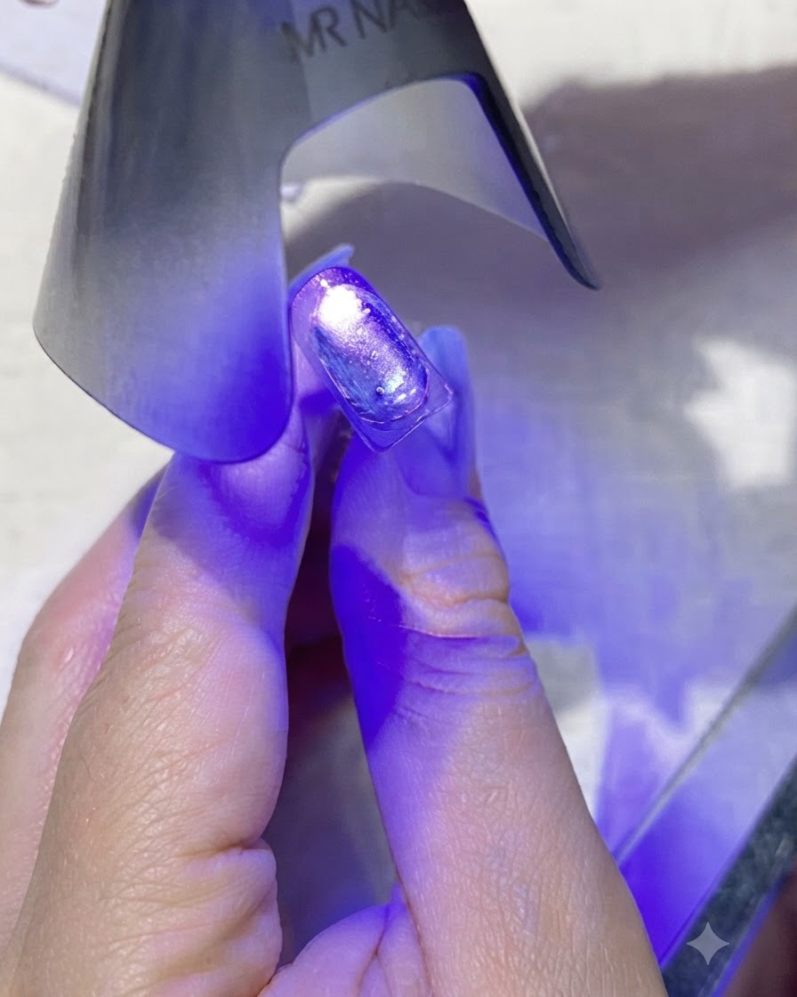 Eine kleine lila Hand-UV/LED-Nagellampe, die violettes Licht direkt über einen beschichteten Nagel abstrahlt.