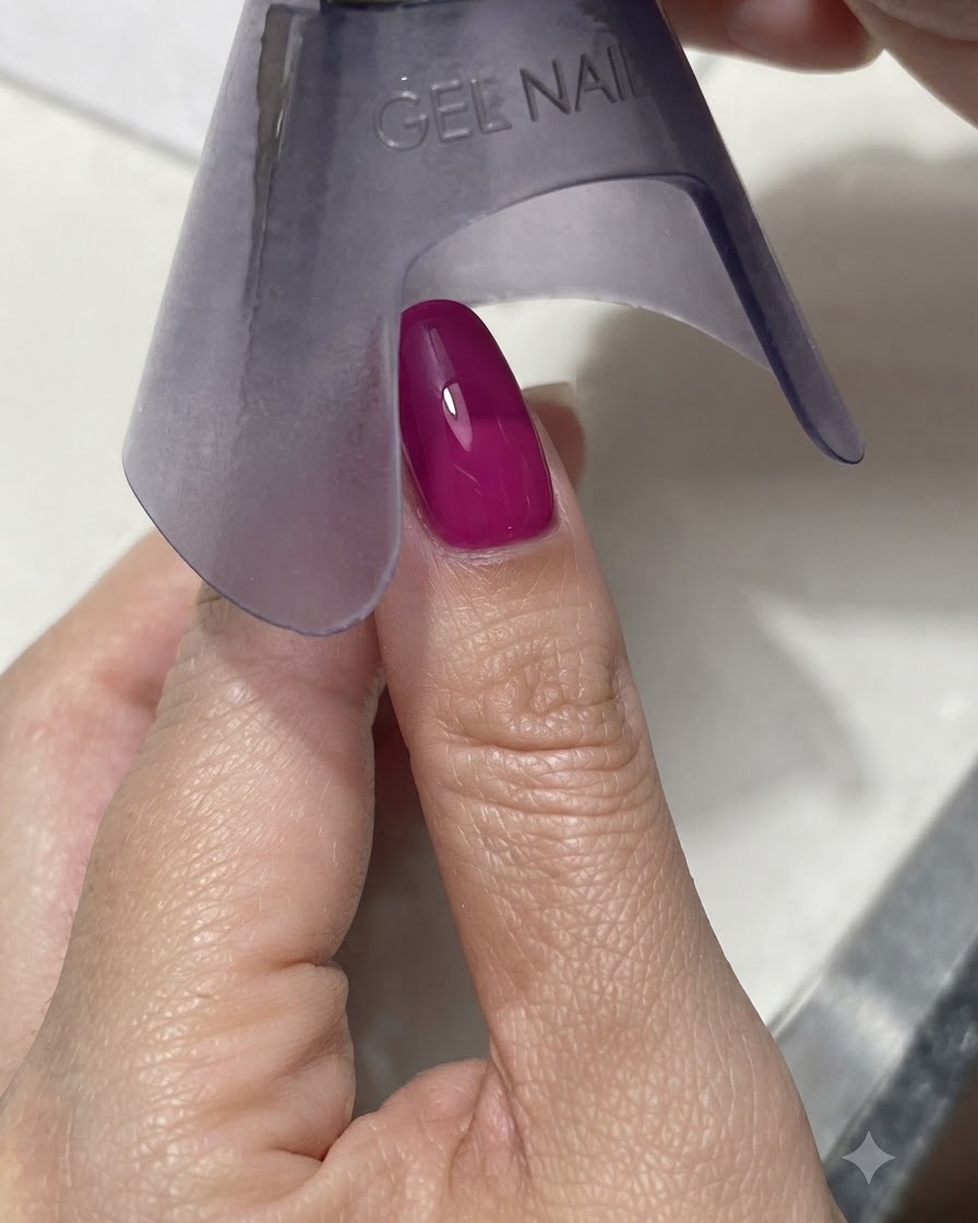 Eine lila Hand-UV/LED-Lampe, die einen lebendigen dunkelmagenta oder blauen Nagel unter hellem Licht aushärtet.