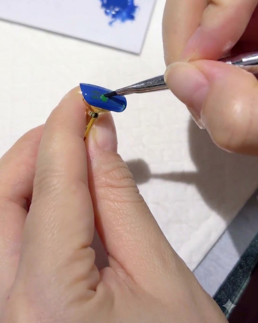 Ein feiner Liner-Pinsel, der winzige dunkelgrüne Blattstriche auf eine blau lackierte Nageloberfläche setzt.
