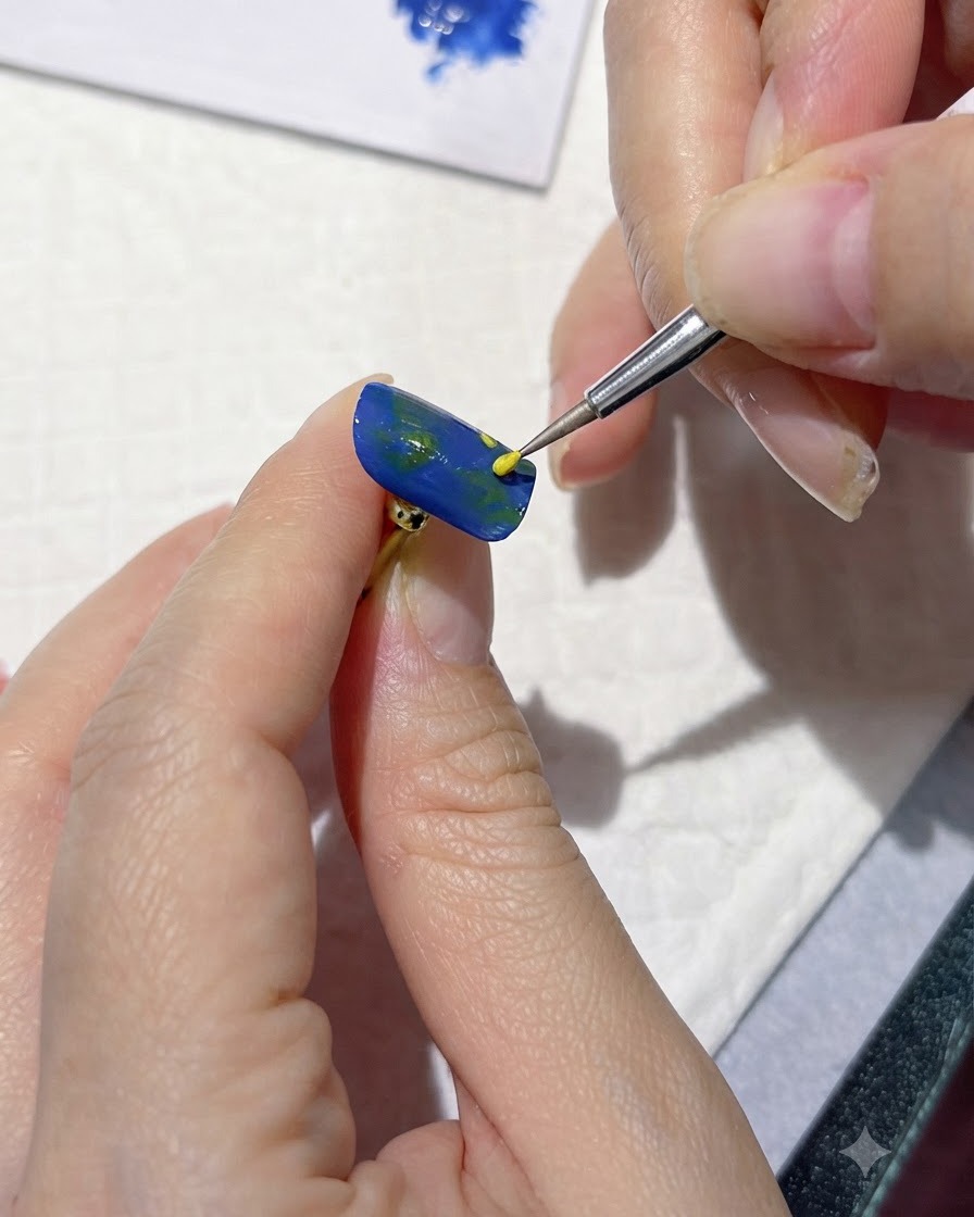 Ein feines Detailwerkzeug, das gelbe Punkte setzt, um Blumenmitten auf einem blauen Nagel zu markieren.