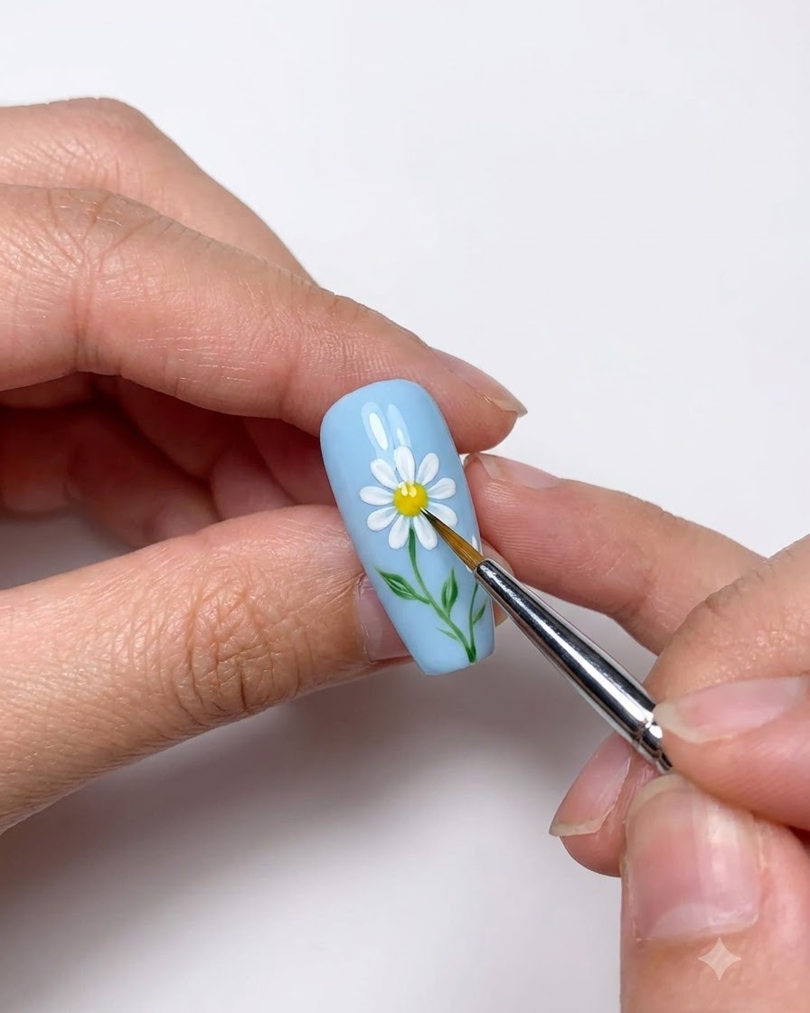 Nahaufnahme eines Dotting-Tools, das ein gelbes Zentrum auf das gemalte weiße Gänseblümchen setzt.