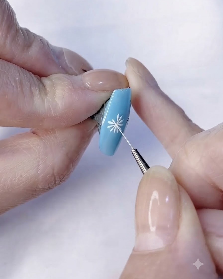 Ein feiner Pinsel vollendet die Details der weißen Blütenblätter eines Gänseblümchen-Nageldesigns.