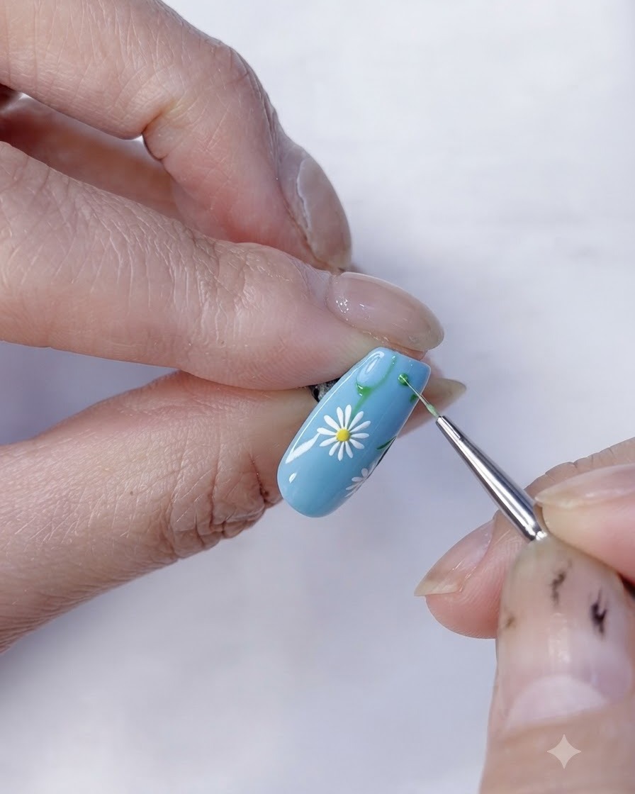 Nahaufnahme eines fertigen Gänseblümchen-Blumen-Nageldesigns auf hellblauer Basis.