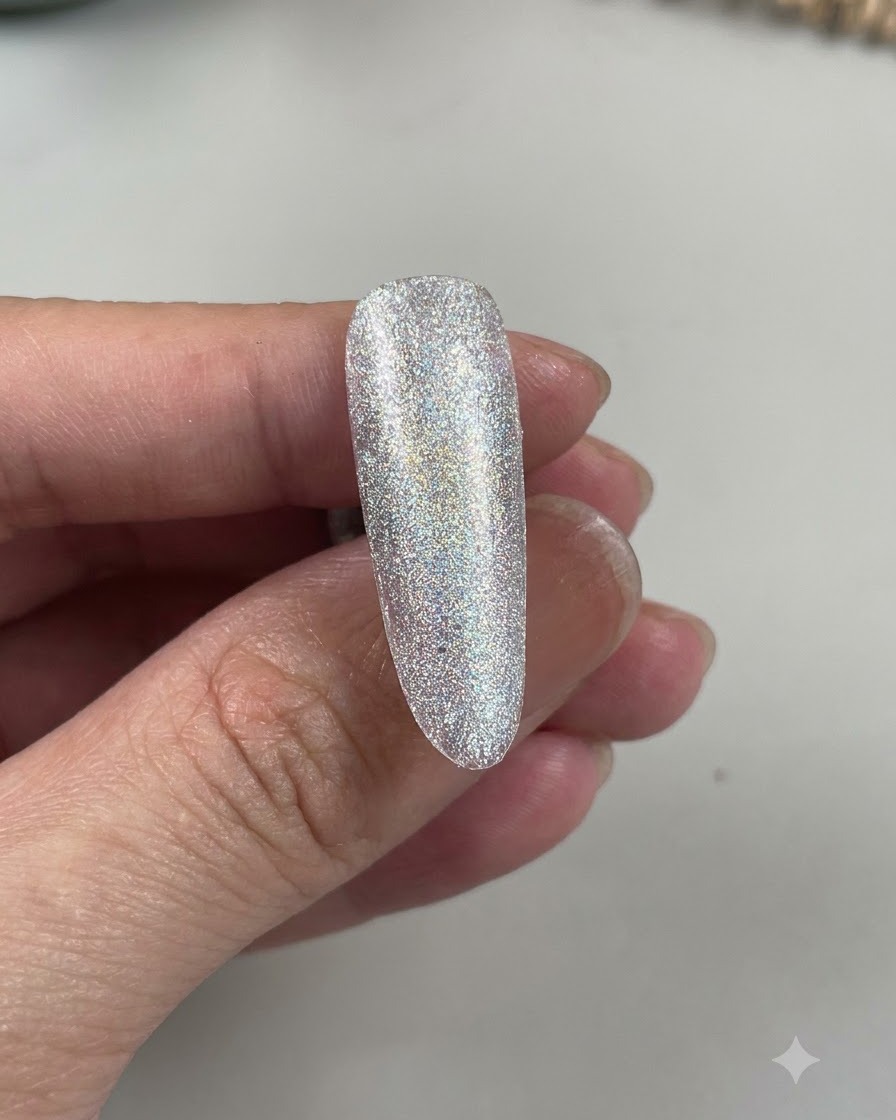 Eine Nahaufnahme eines mandelförmigen Nagels, die einen hellblauen Farbton zeigt, der über einer funkelnden Basis aufgetragen ist.