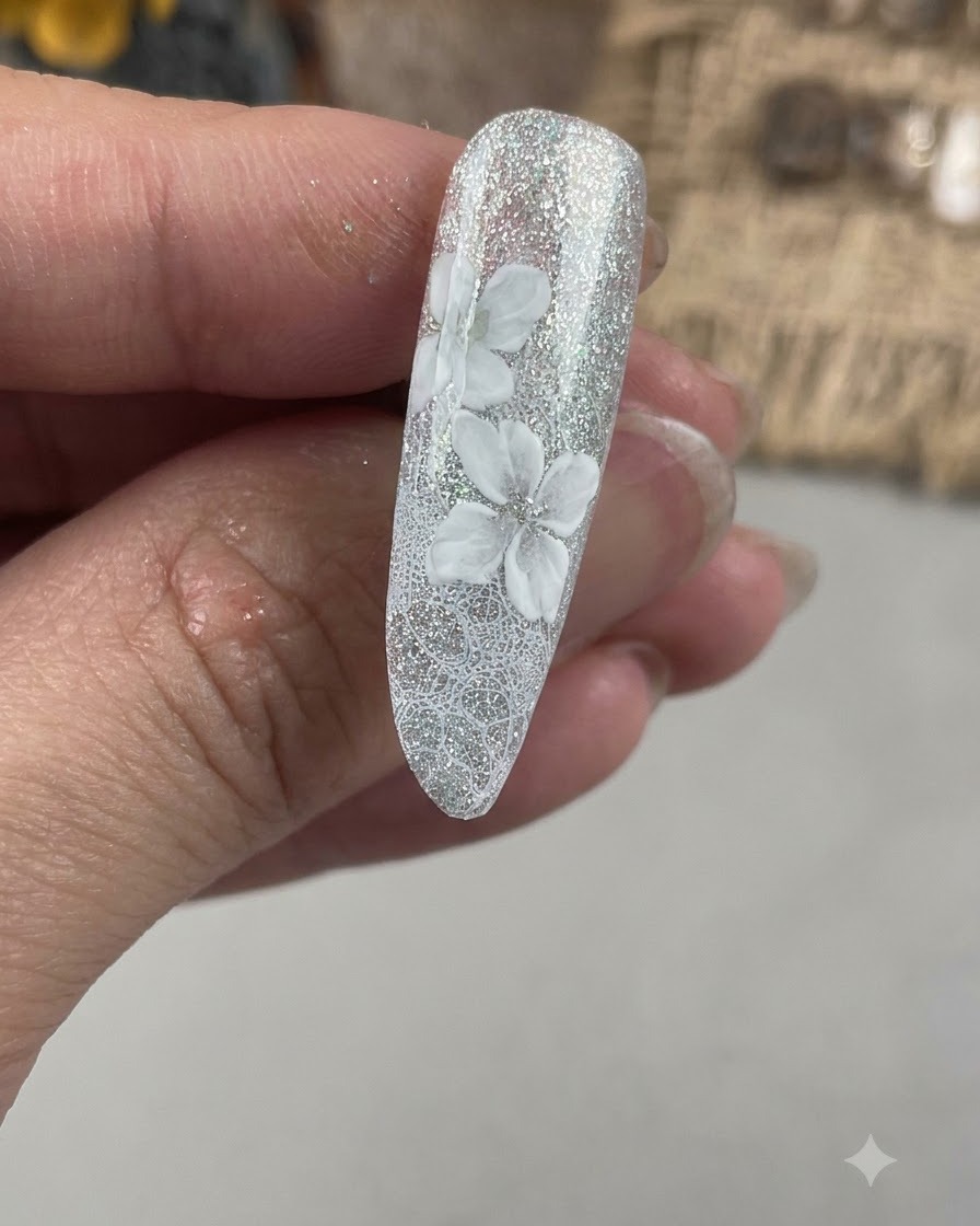 Eine Nahaufnahme eines Fingernagels, die eine zweite Schicht weißer Blütenblätter zeigt, die versetzt zur anfänglichen Blumenbasis gemalt werden.